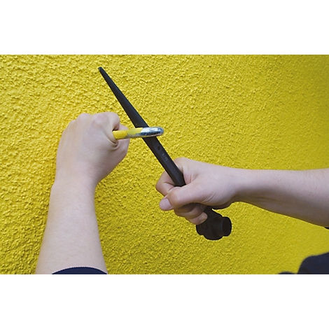 Hände halten einen schwarzen Stab mit einem gelben Werkzeug. Der Hintergrund ist eine gelbe Wand.